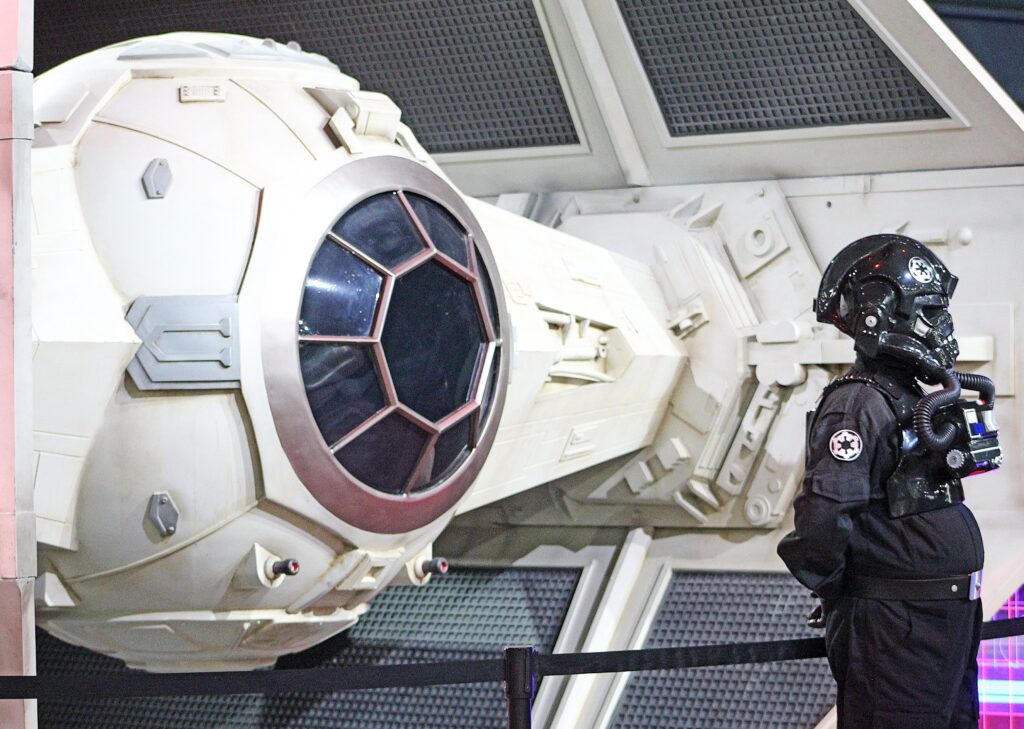 An Imperial fighter pilot stands guard by Darth Vader&rsquo;s TIE fighter.